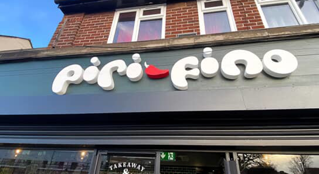 exterior signage of piri fino - it is playful and white with a red pepper in the middle